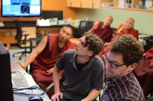 Lab staff and Monks looking at computer screen
